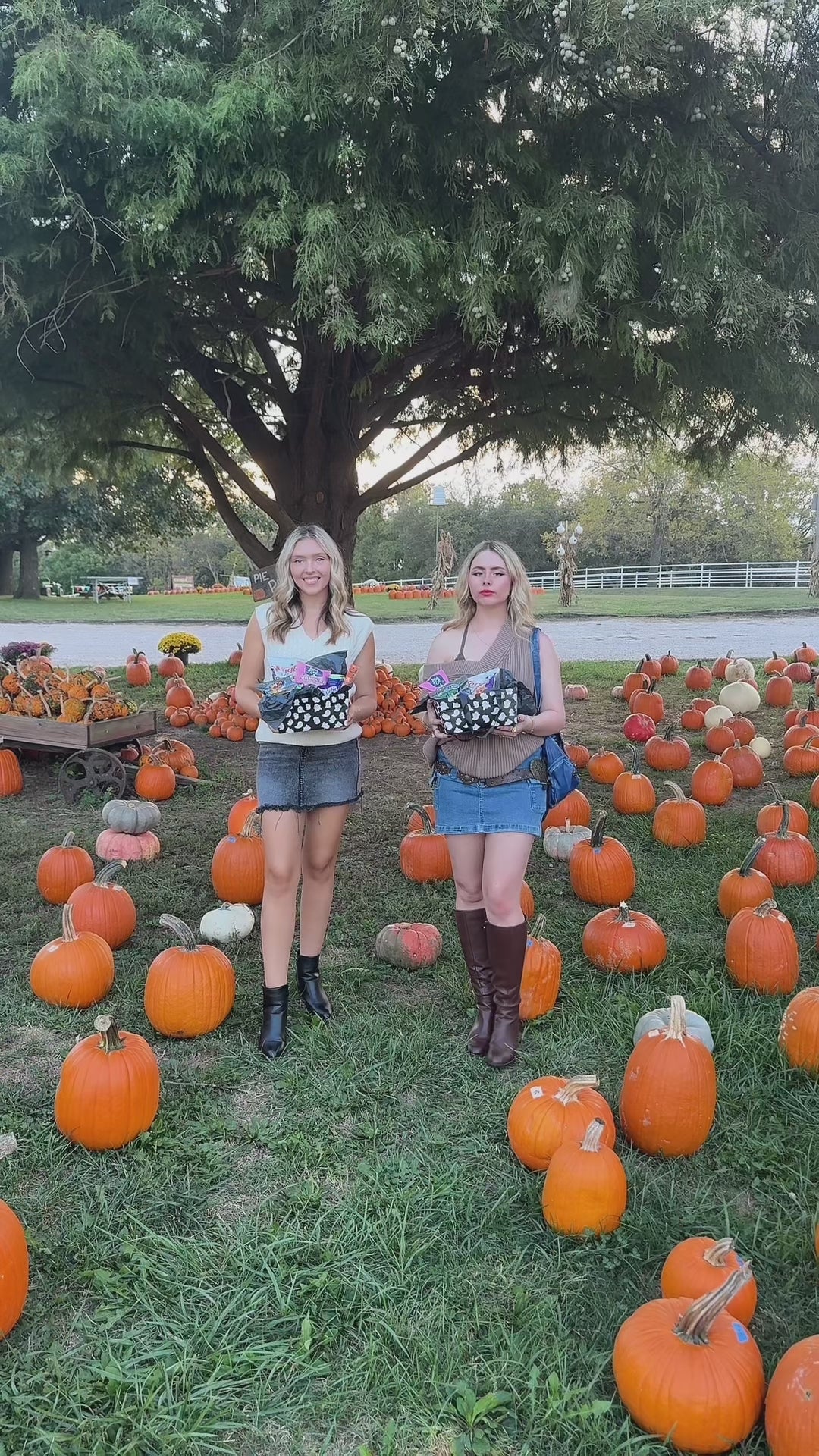 Glutique founders Elizabeth and Alyssa walking through a pumpkin patch holding their Boo Box, a gluten-free fall snack box designed for college students